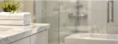 Spotless marble bathroom vanity with folded towels and glass shower